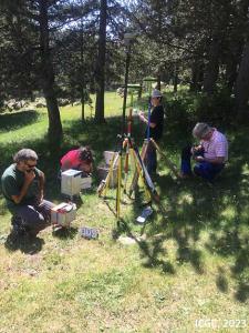 Quatre tècnics estan situant instruments en superfície per a mesures geofísiques en un prat amb arbres.