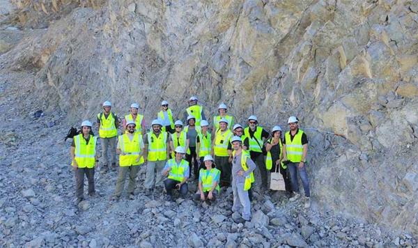 Grup de participants del projecte europeu GO-Forward, amb armilles i cascos de seguretat, davant d’un aflorament de roca granítica fracturada durant una jornada de treball de camp.