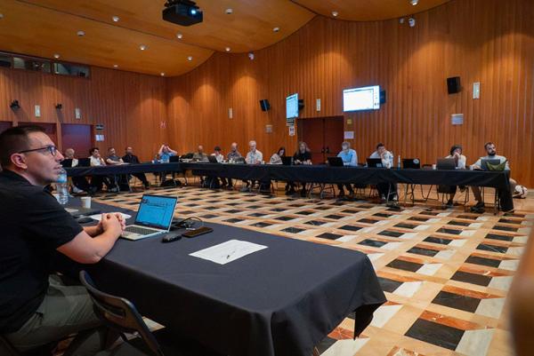 Participants de GO-Forward durant una sessió de treball, asseguts al voltant de taules amb ordinadors portàtils i amb pantalles de presentació al fons de la sala.